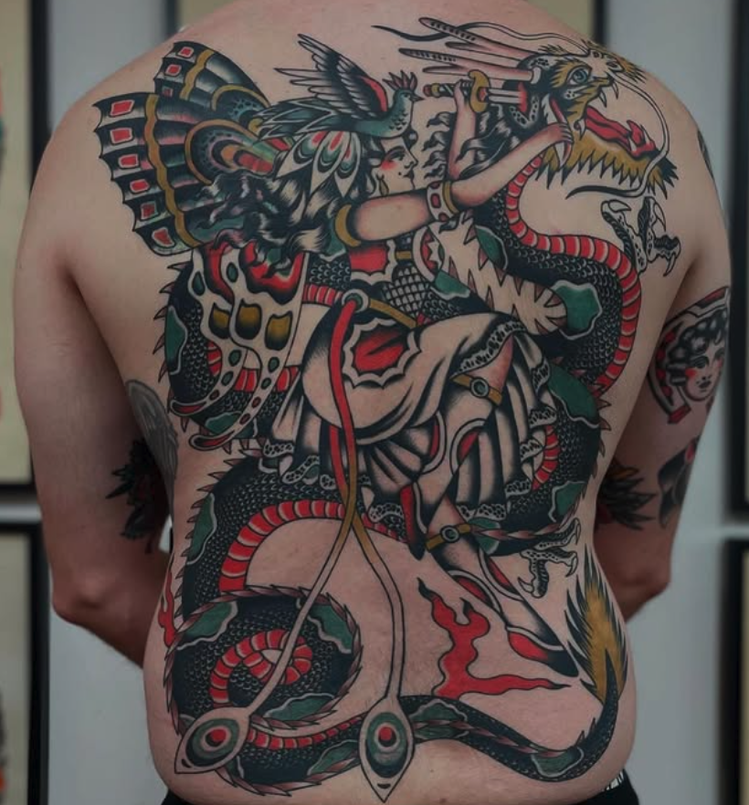 Colorful traditional Japanese dragon tattoo on person's back with a woman riding it, holding a spear, and a bird with wings outstretched.