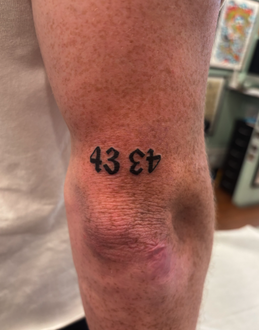 A tattoo with the numbers '43 43' on the back of a person's leg, near the knee.