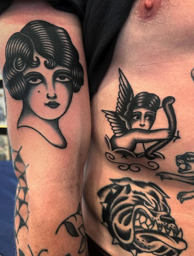 Tattoo of a vintage woman with curly hair on person's arm and a tattoo of a winged person aiming an arrow on person's chest