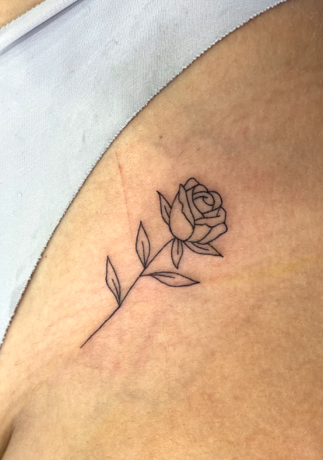 Simple line drawing of a rose flower tattoo on skin, with leaves and a stem.