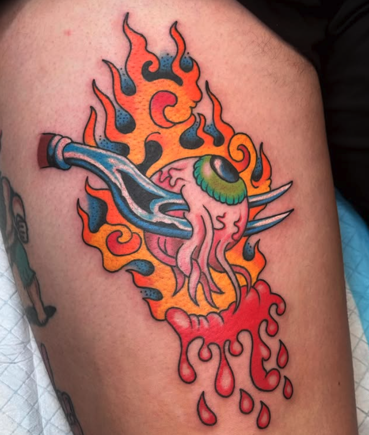 A colorful tattoo of a squid-like creature with one large eye, surrounded by flames and melting red liquid.