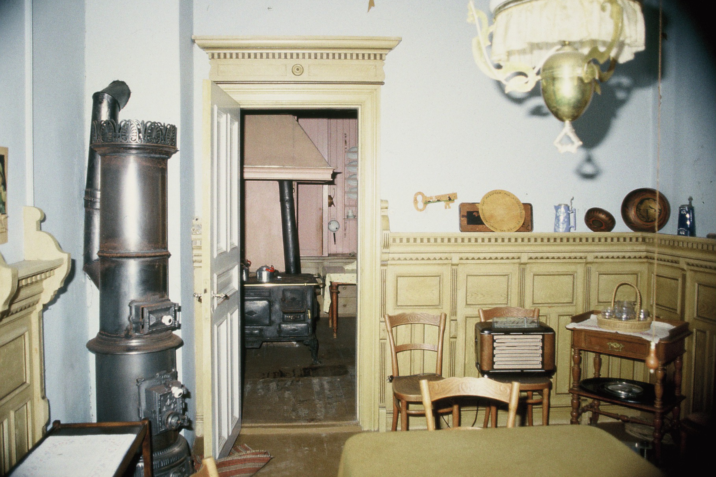 Motiv fra spisestuen tatt før renoveringen av huset startet i 1986. Både bryst­nings­panelet, støpejernsovnen og den gamle komfyren finnes i huset i dag. Foto: Ingjerd Asbjørnsen