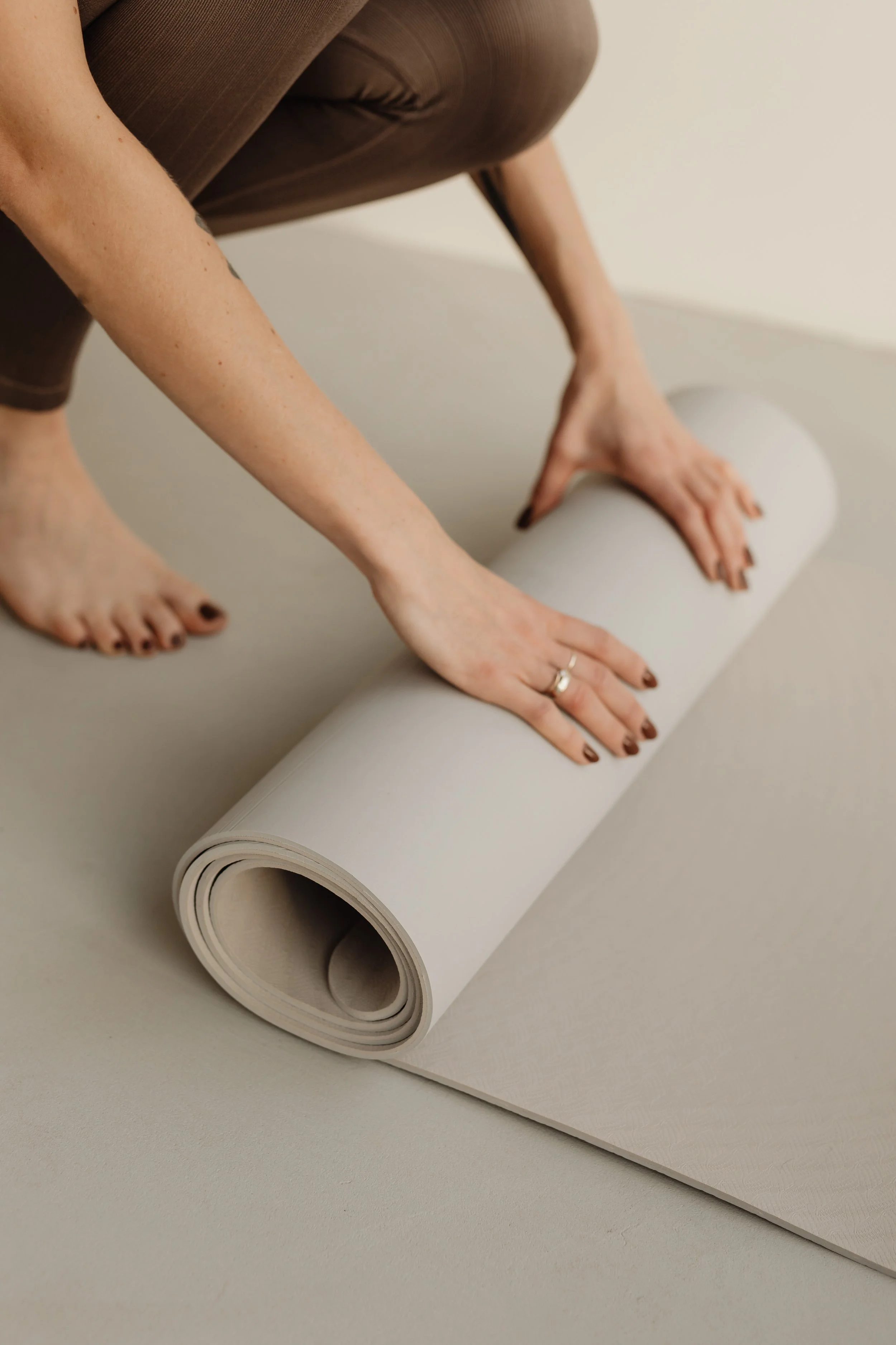 Person rolling out a yoga mat on the floor.
