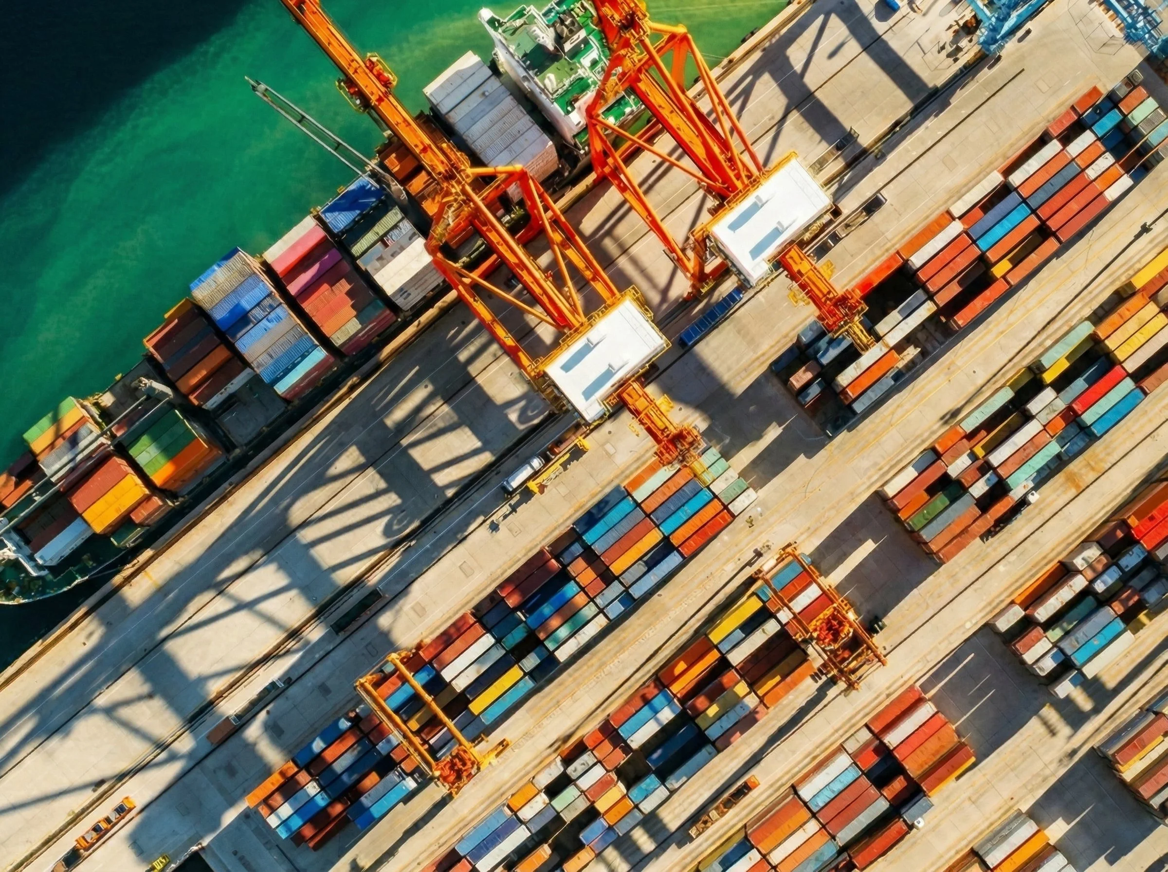 Aerial view of a busy shipping port with containers in various colors and cranes.