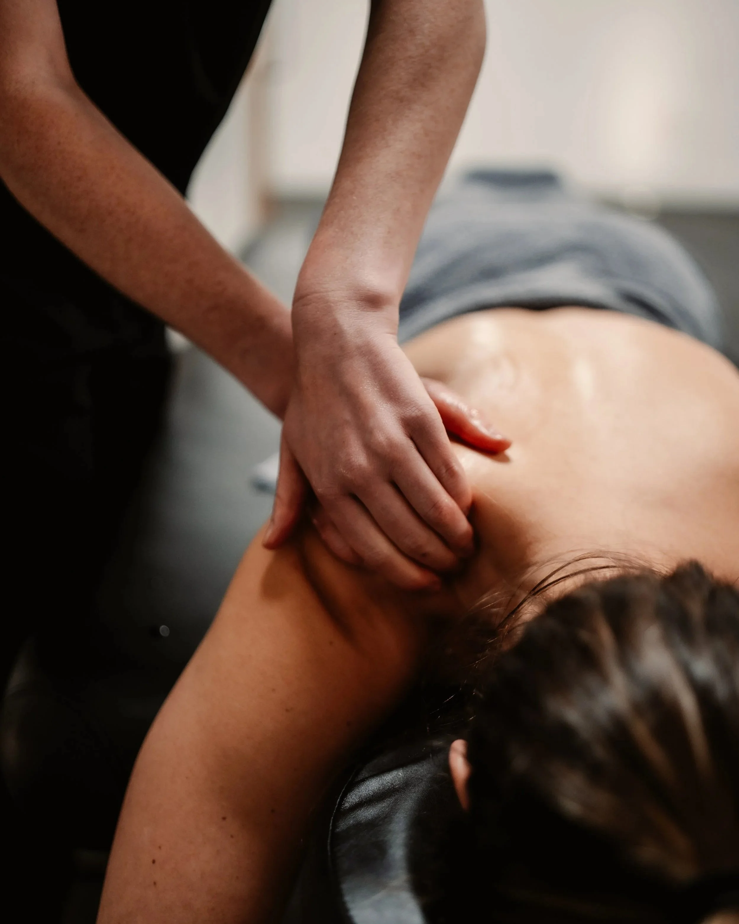 Person receiving a massage on their shoulder from a masseuse in a massage therapy setting.