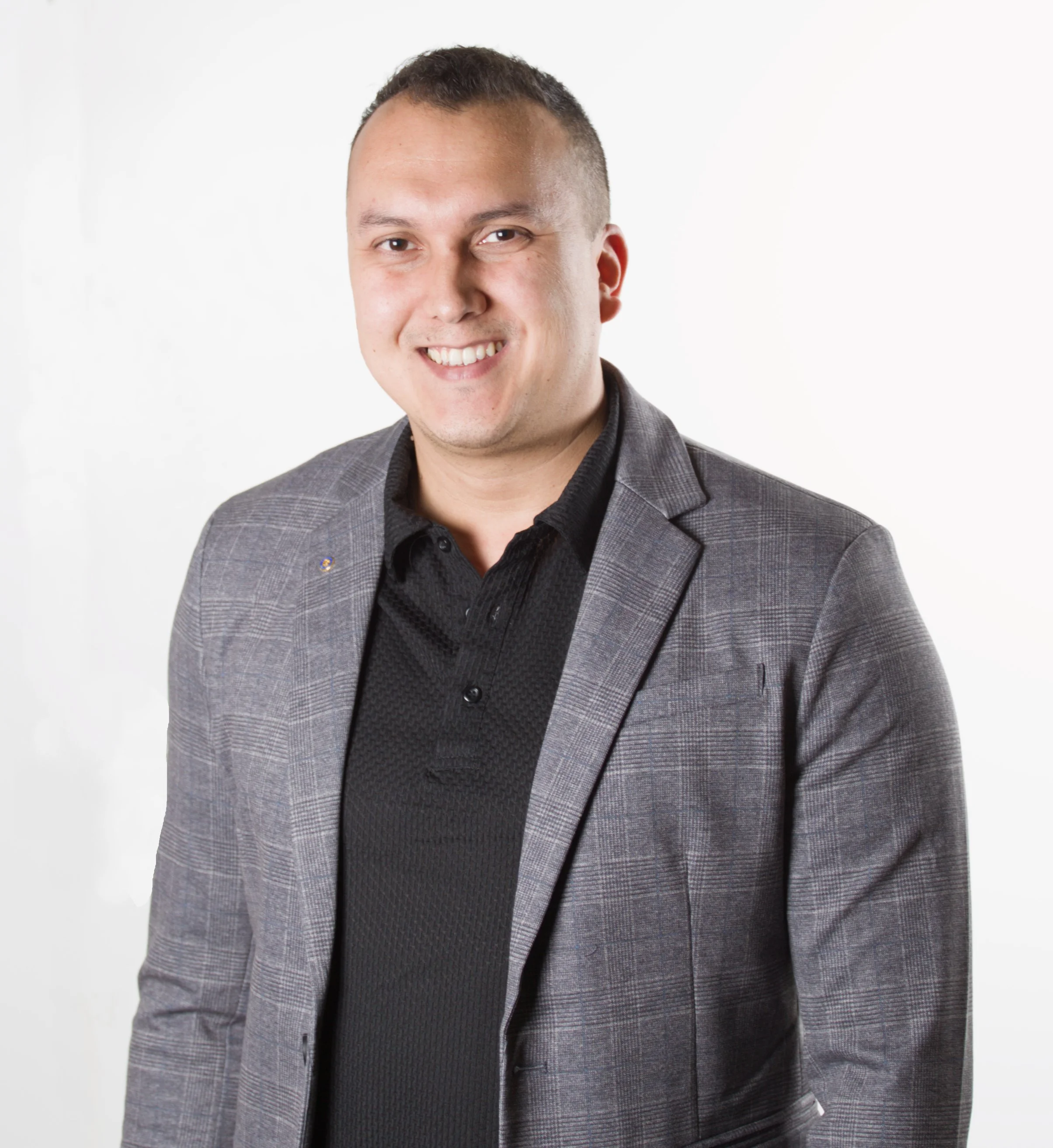 Lächelnder Mann in dunklem Hemd und grauem Anzug vor weißem Hintergrund