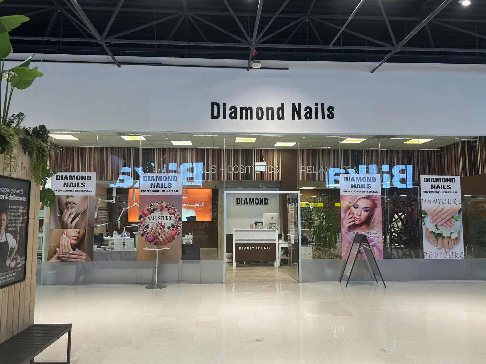 Storefront with large sign that reads 'Diamond Nails' and promotional posters featuring images of manicured hands.
