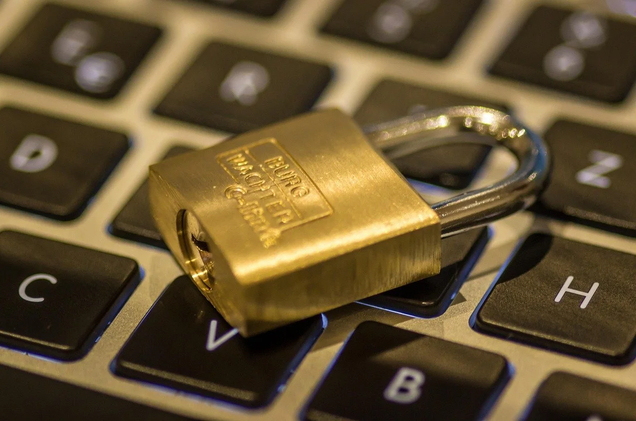 A brass padlock resting on a computer keyboard.