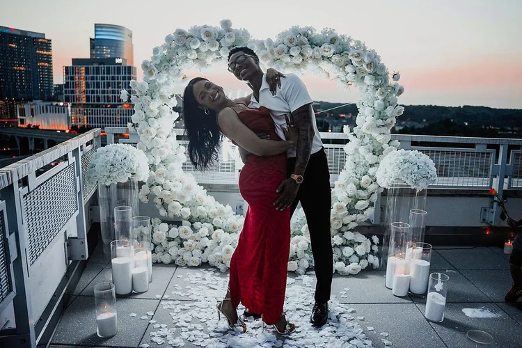Happy couple embracing in front of a white rose heart arch, glass candle holders and white petals at Mia Penthouse, the rooftop space at The Watermark Hotel in Tysons Corner, McLean, Virginia