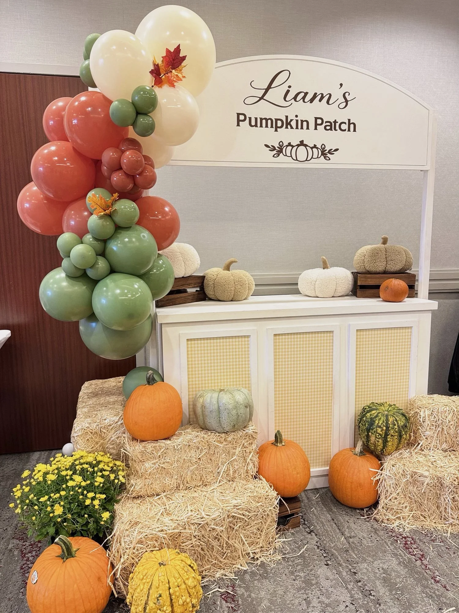 Pumpkin patch party stand with hay bales, pumpkins, mums and an autumn balloon garland at Courtyard by Marriott Tysons McLean in Virginia