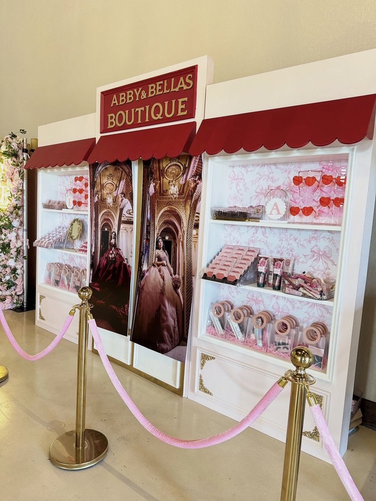 Boutique storefront backdrop rental with red awning, shelves of party favors and gold stanchions at a quinceañera
