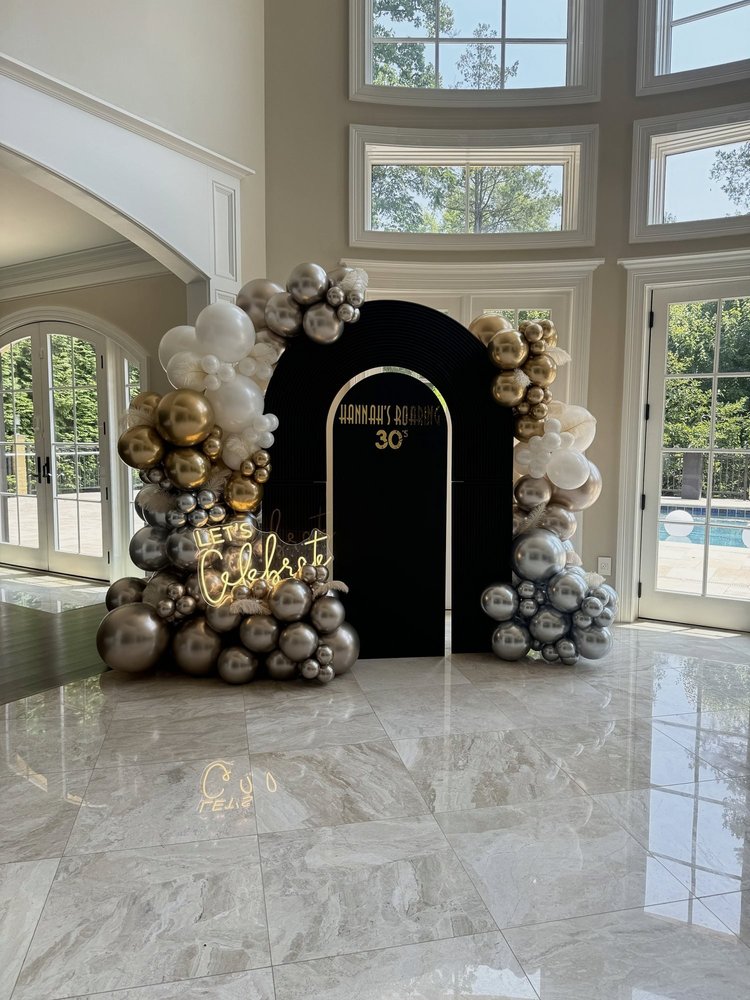 Roaring 20s themed 30th birthday with a black arch backdrop, Let's Celebrate neon sign and gold, silver and white balloon garlands with feathers in a McLean, Virginia home