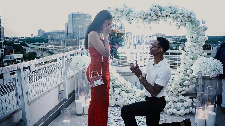 Surprise rooftop proposal at sunset with a white floral heart arch, neon sign and candles at Mia Penthouse, the rooftop space at The Watermark Hotel in Tysons Corner, McLean, Virginia