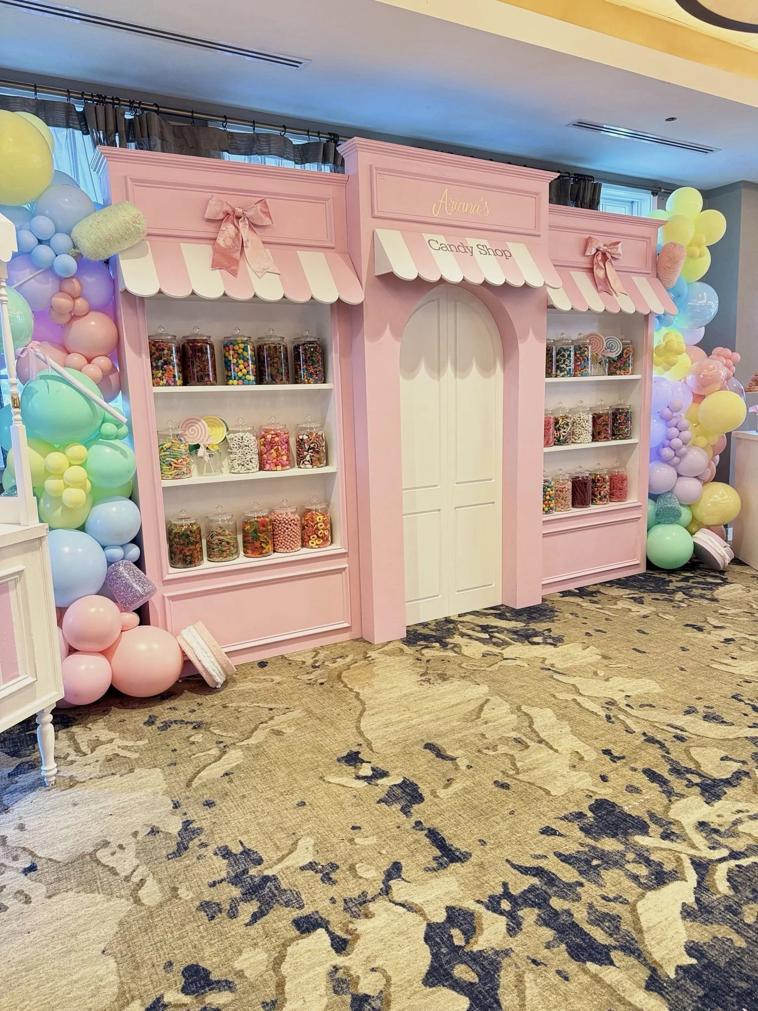 Pink candy shop storefront backdrop rental with candy jars and pastel balloon garlands at a 5th birthday party in Virginia