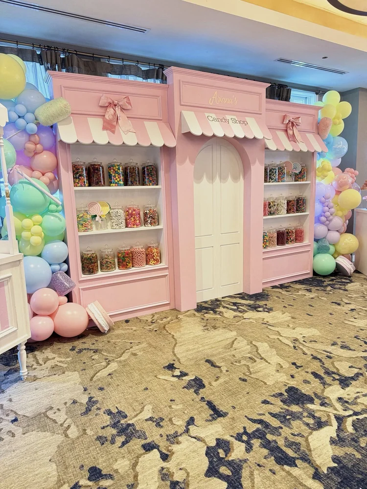 Pink candy shop storefront backdrop rental with candy jars and pastel balloon garlands at a 5th birthday party in Virginia