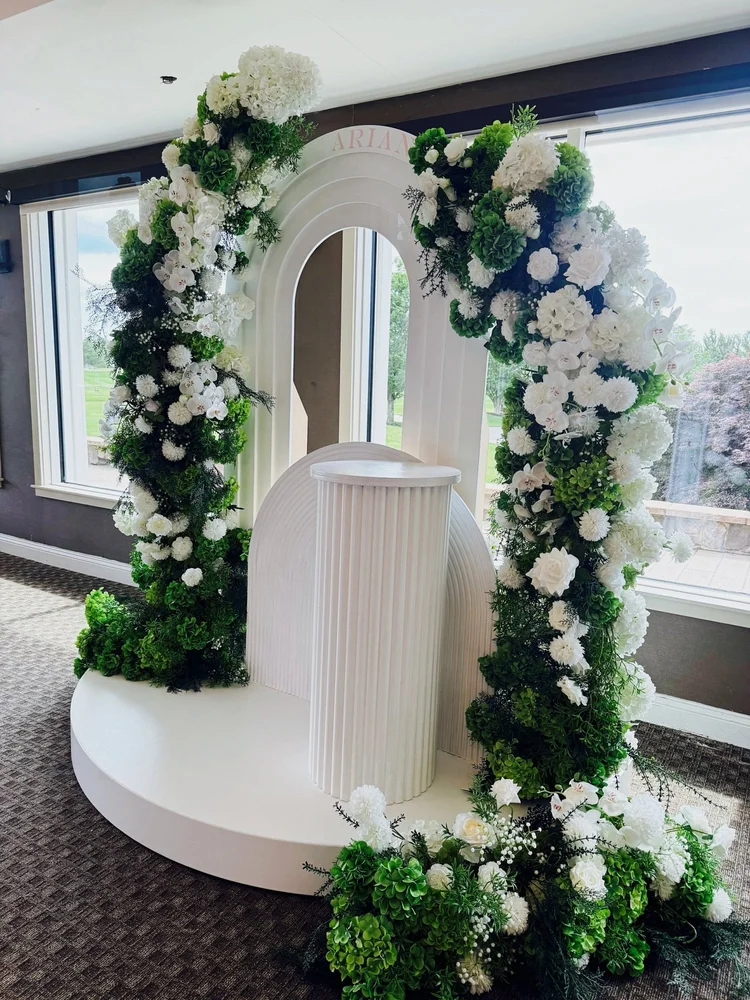 White arch backdrop with round stage, fluted pedestal and a white and green floral arch with hydrangeas, roses and orchids at Chantilly National Golf & Country Club in Centreville, Virginia