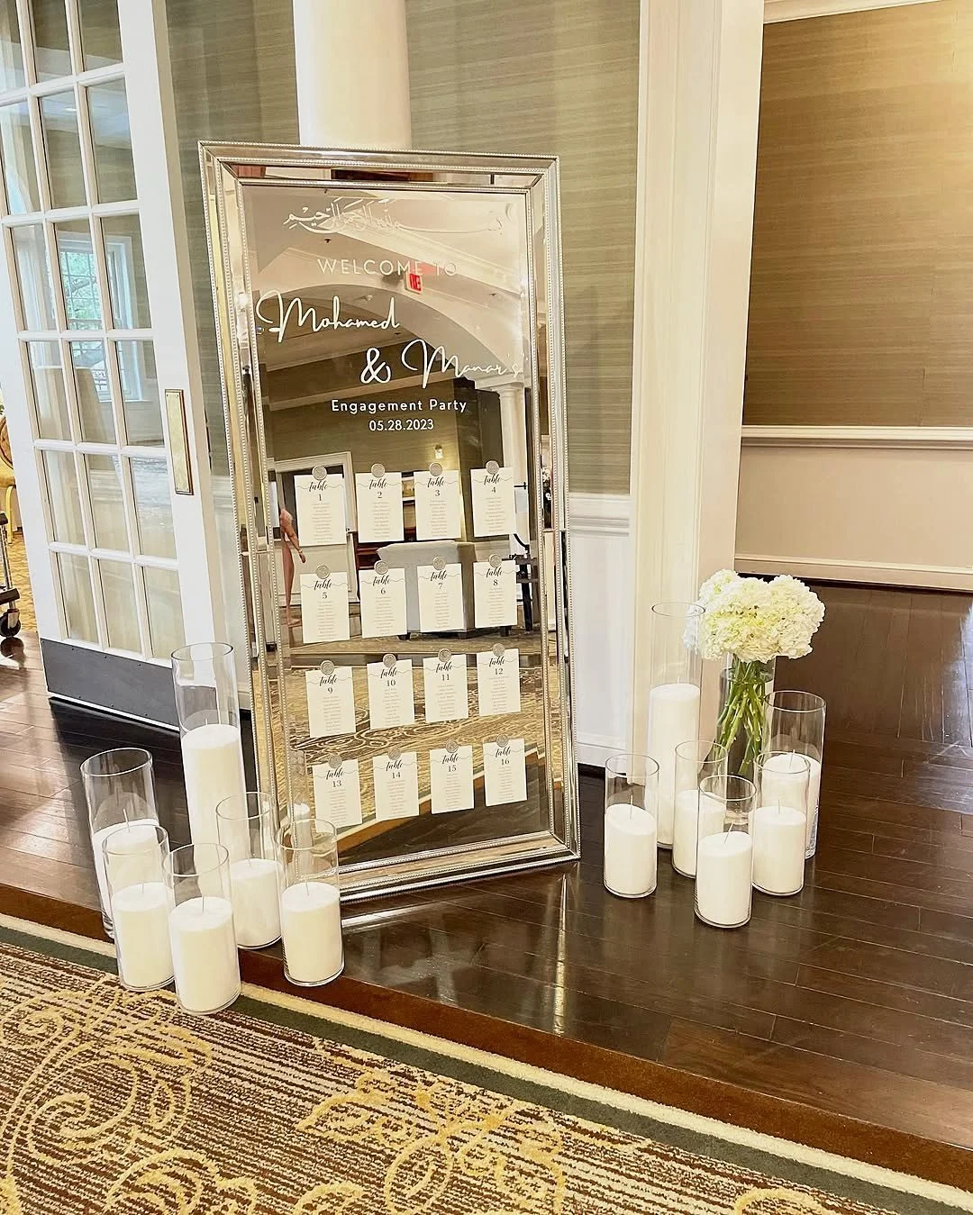 Engagement party welcome mirror with a seating chart, glass pillar candles and white hydrangeas at the Country Club of Fairfax in Virginia