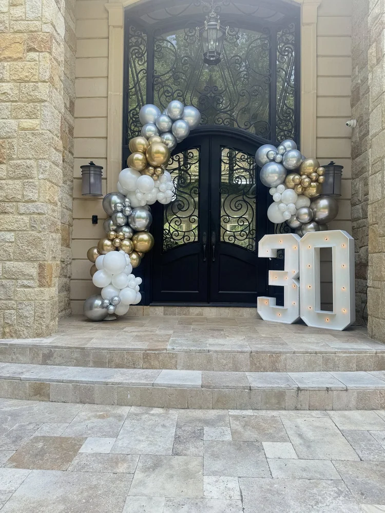 Light-up marquee numbers 30 with a gold, silver and white balloon garland framing a home entrance in McLean, Virginia