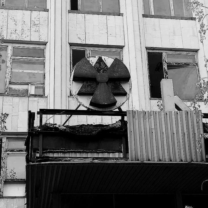 A building with a nuclear warning symbol mounted above the entrance, in black and white.