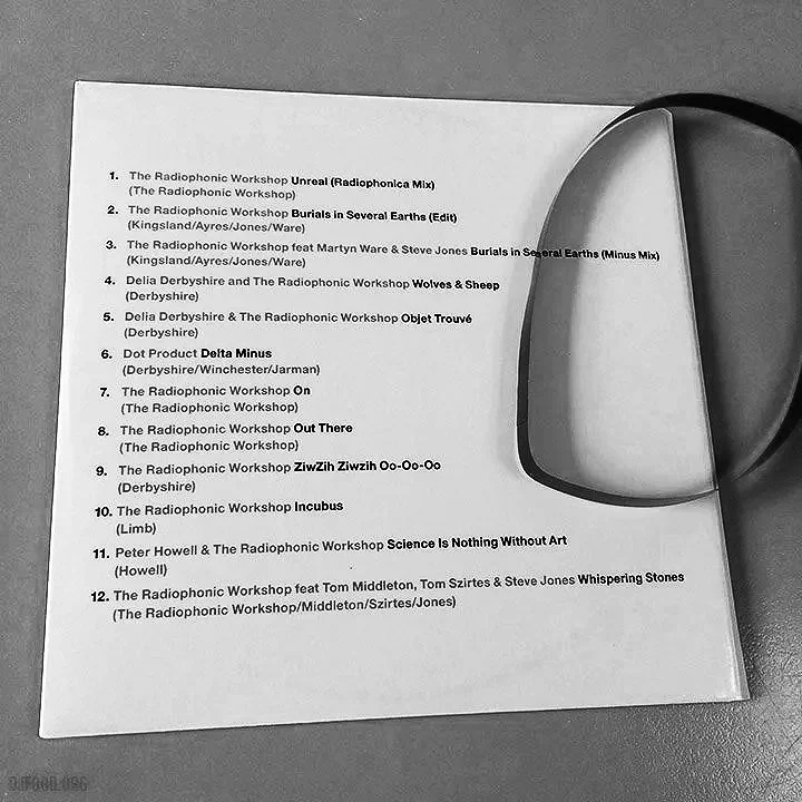 A printed list of song titles and artists on a sheet of paper with a metallic object partially covering the right side.