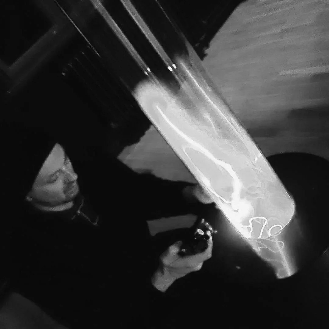 A person playing an arcade game in a dark environment, with visible bright lights and reflections on the game screen.