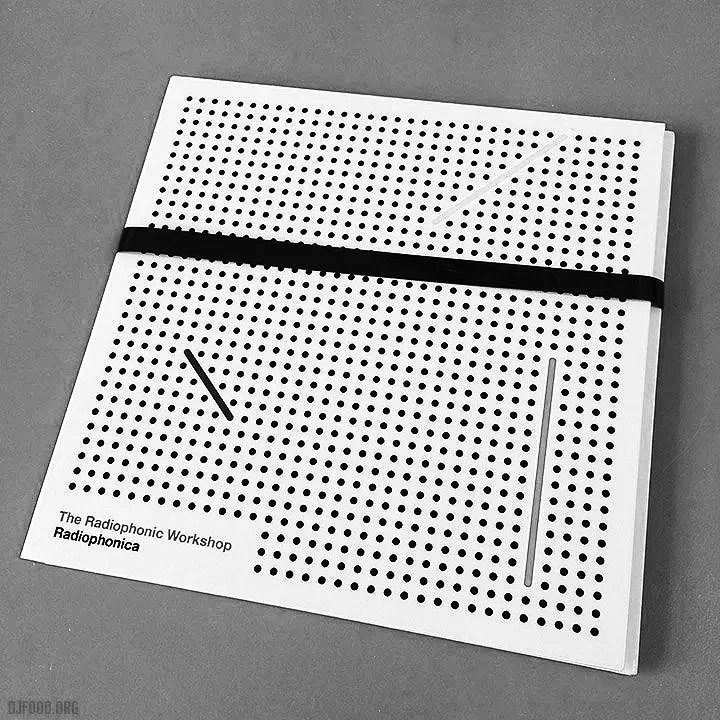 A white notebook with black dots, a black elastic band, and a thin gray line on a gray surface.