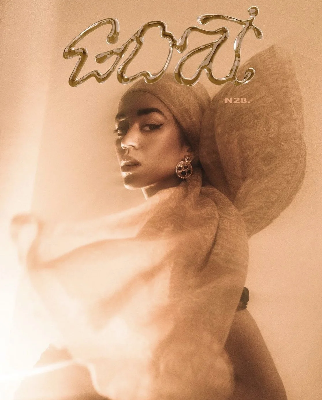 Una mujer con coleta, sombra de ojos y labios pintados, lleva un arete grande y un pañuelo en la cabeza, posa frente a un fondo de color beige con un letrero de neón dorado que dice 'Vogue' y el número 'N28'.