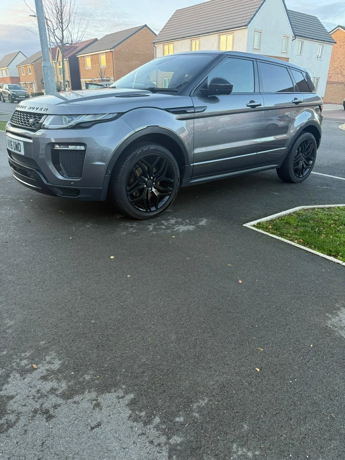 A gray Range Rover SUV parked in a residential area with houses in the background.