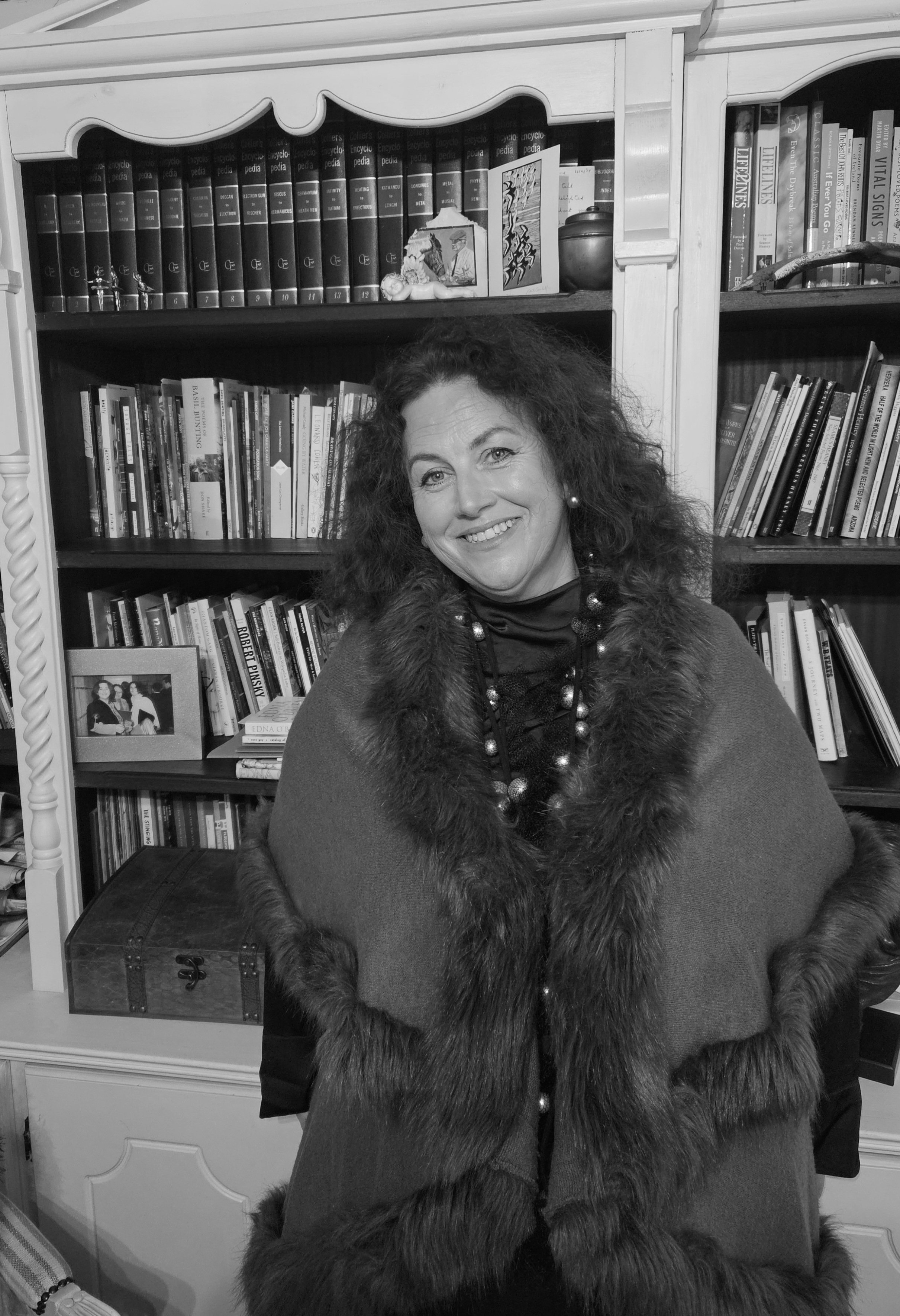“Portrait of a smiling woman in front of a bookshelf, representing the site’s author.”
