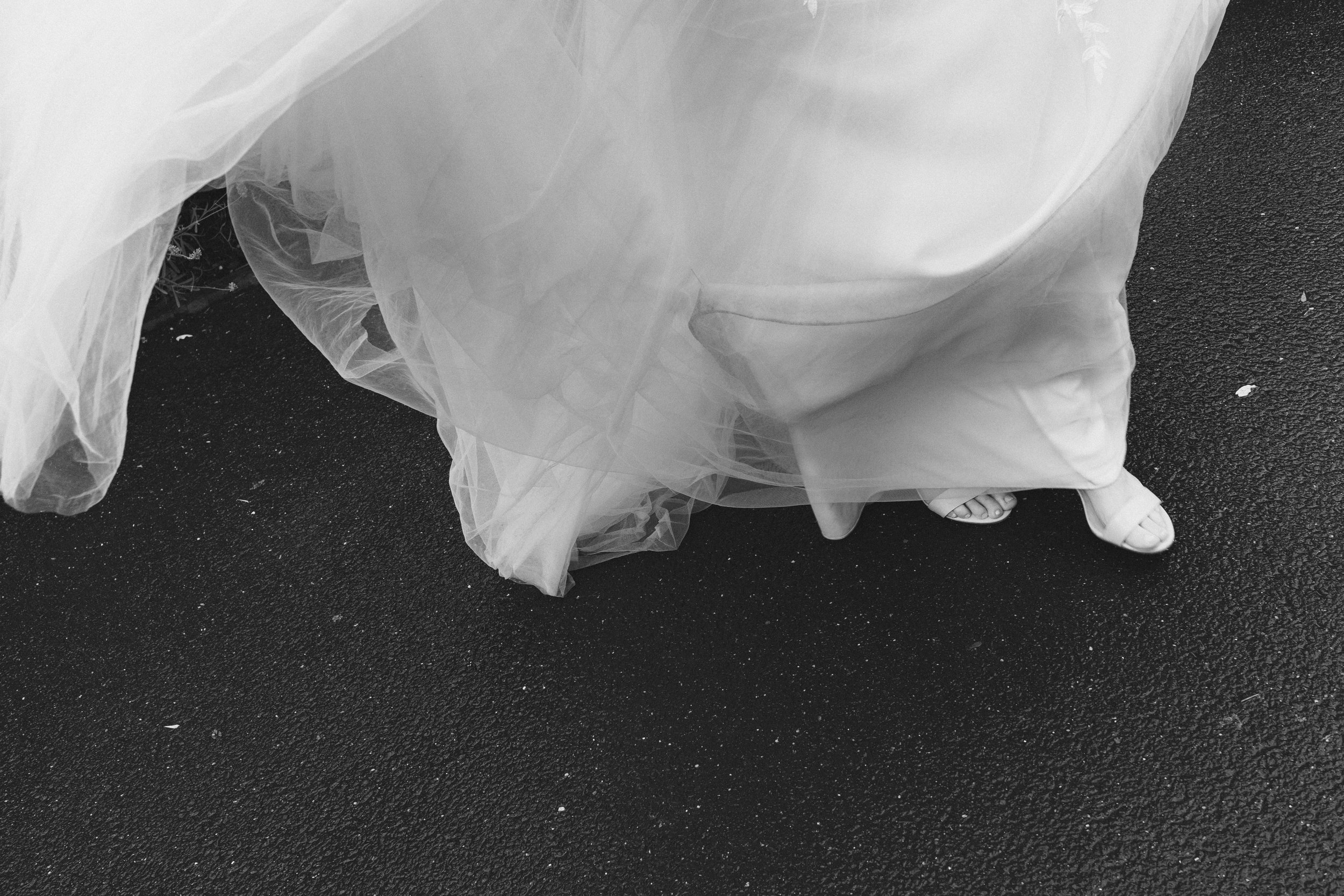 Schuhspuren und Schuhe einer Person in einem weißen Kleid auf Asphalt