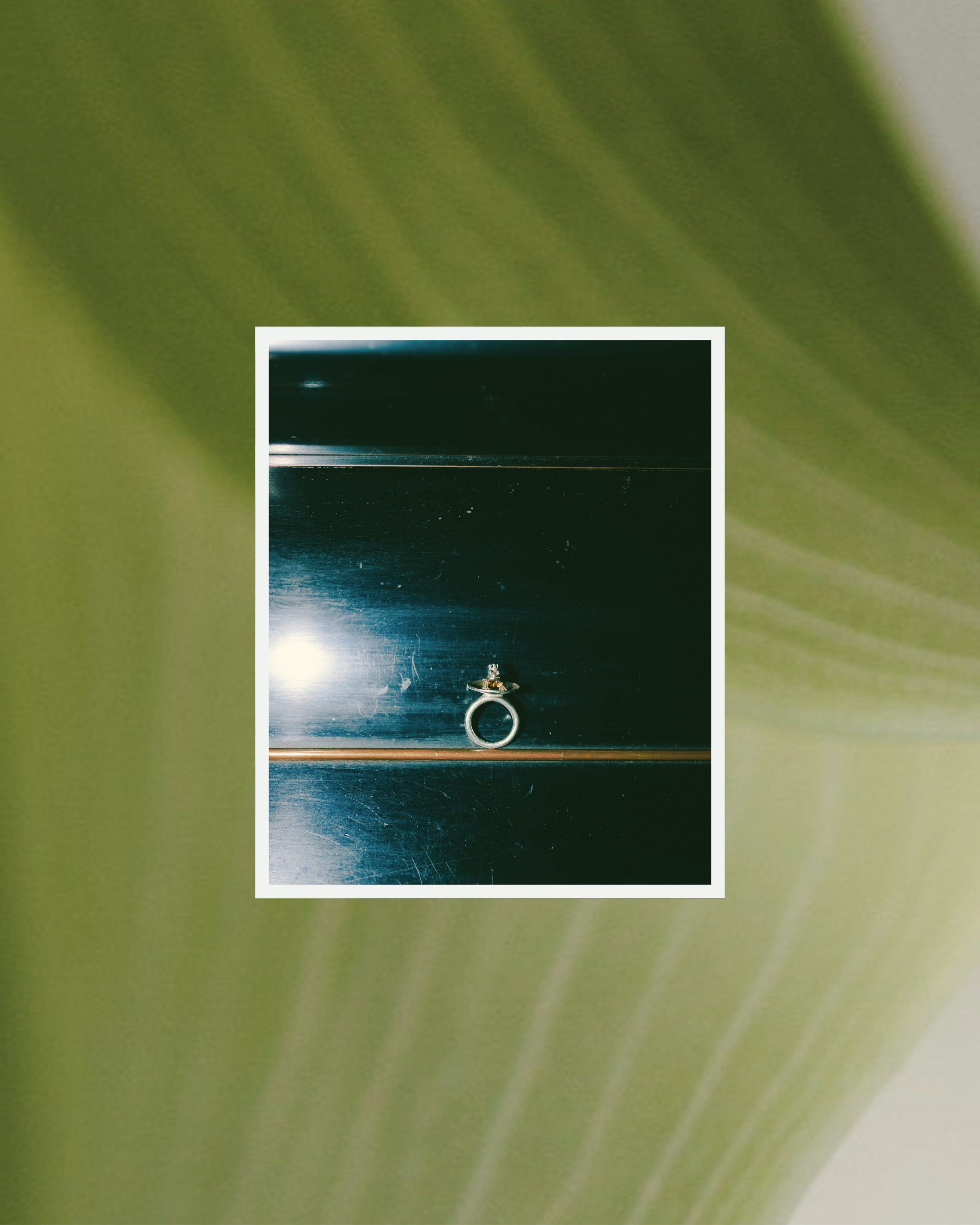 Ein Ring liegt auf einer schwarzen, reflektierenden Oberfläche, vermutlich Metall, mit Lichtreflexen.