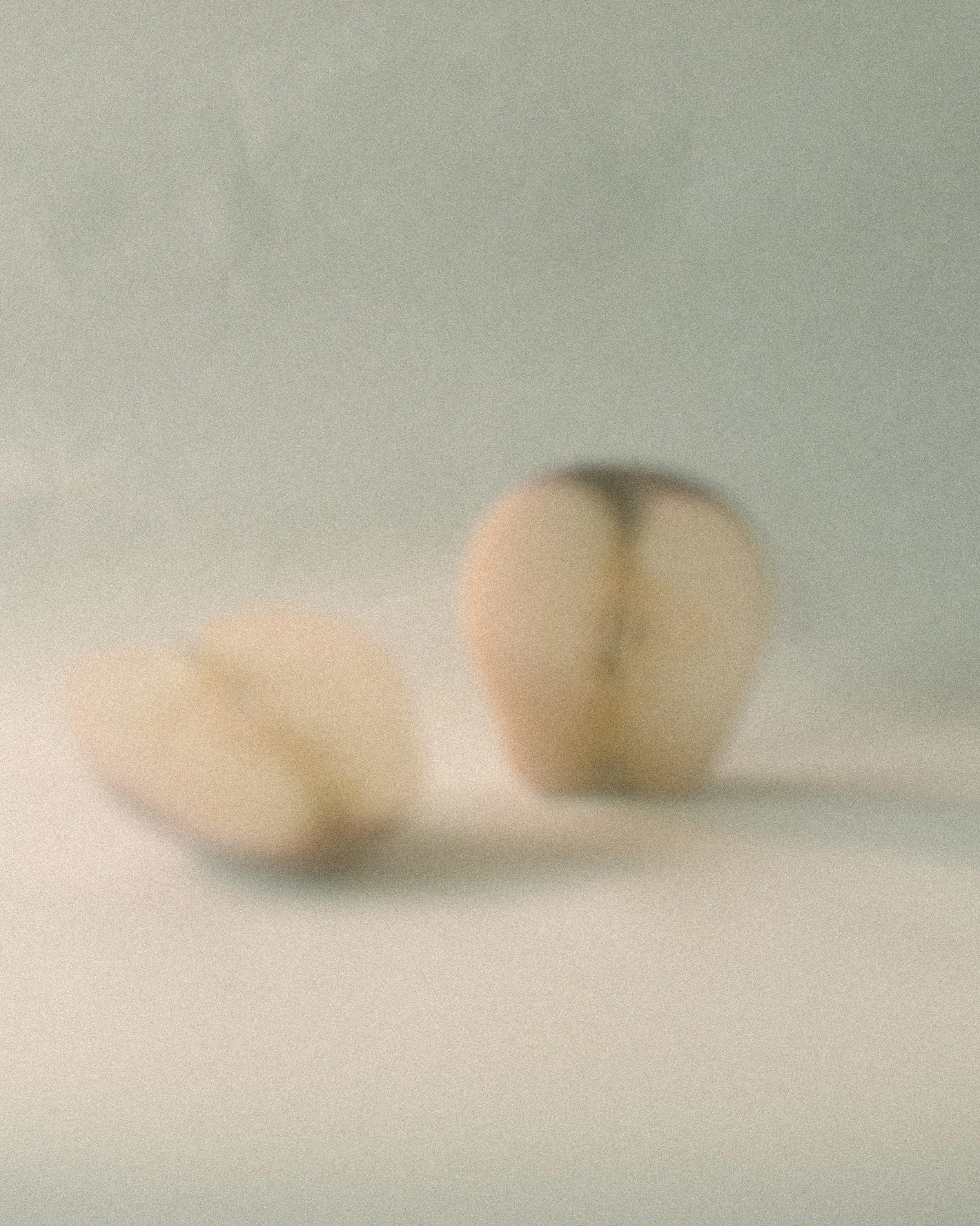 Zwei Ohrstöpsel auf einem weißen Untergrund, unscharf fotografiert.