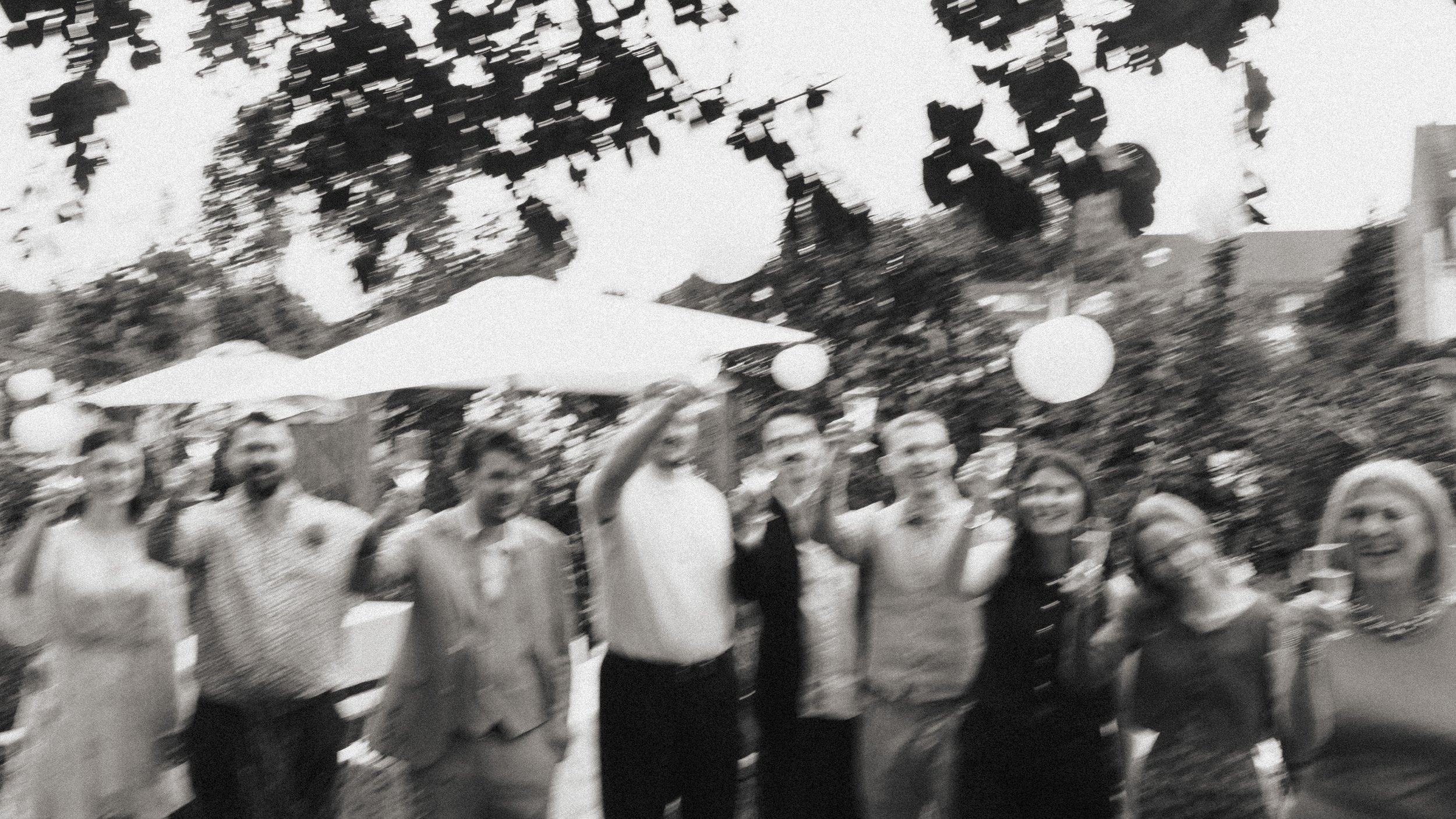 Gruppe von Menschen bei einer Party im Freien, einige sind am Lachen und einige sind im Gespräch, bunte Lampions hängen in den Bäumen.