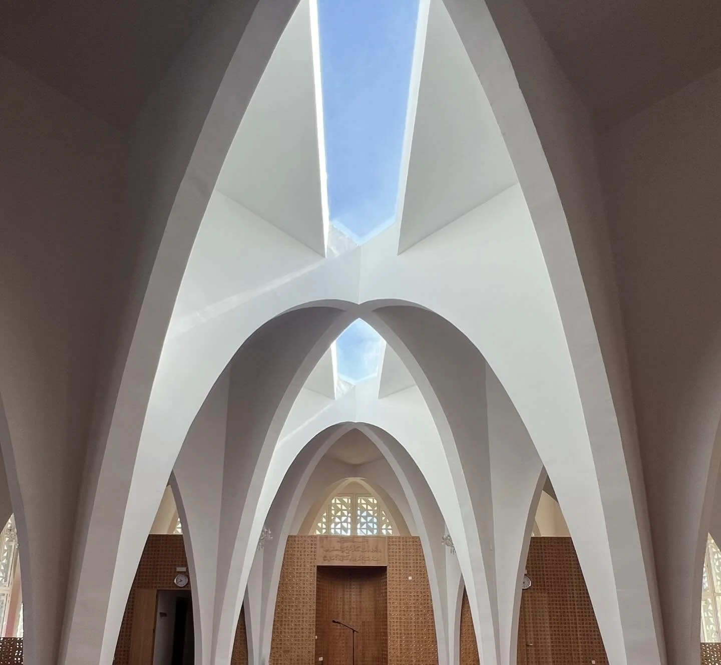 Discover the final interiors of the mosque ! 

The project features white concrete arches and a wooden maqsura with geometric shapes.

The dialogue between the softness of the wood and the purity of the concrete creates a harmonious sensory and spiri