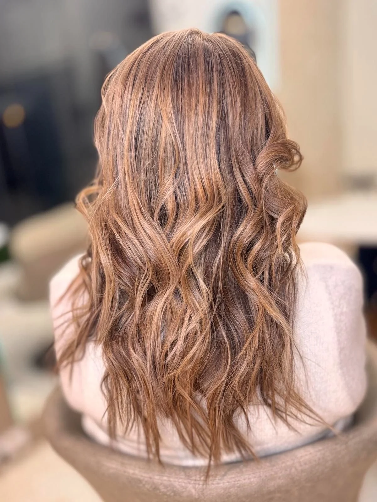 Back view of a woman with long, wavy, light brown or caramel-colored hair
