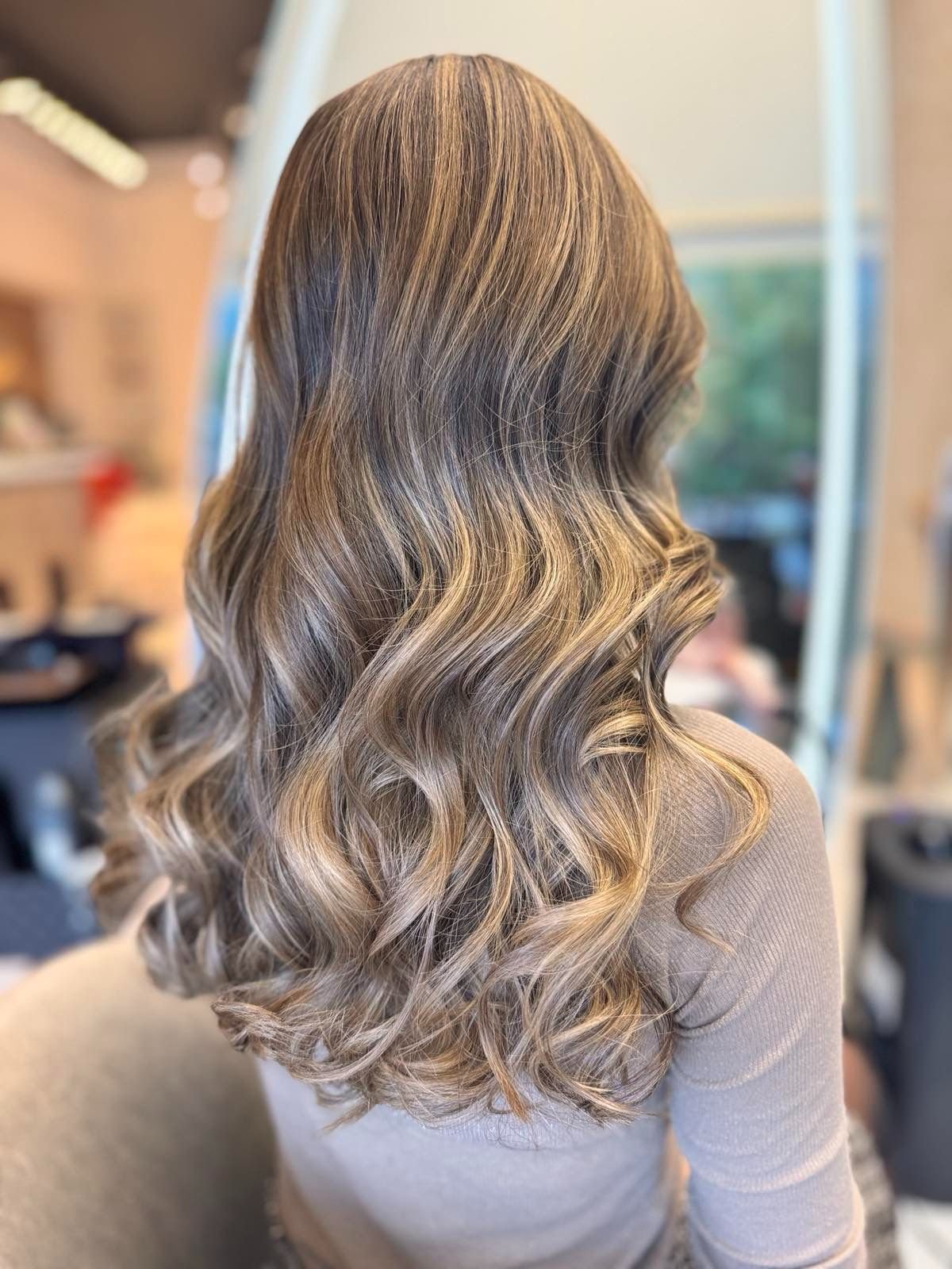 Back of a woman with long, wavy, blonde hair.