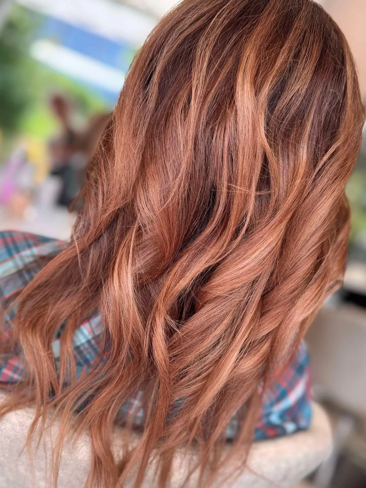 Close-up of wavy, copper-colored hair with highlights.