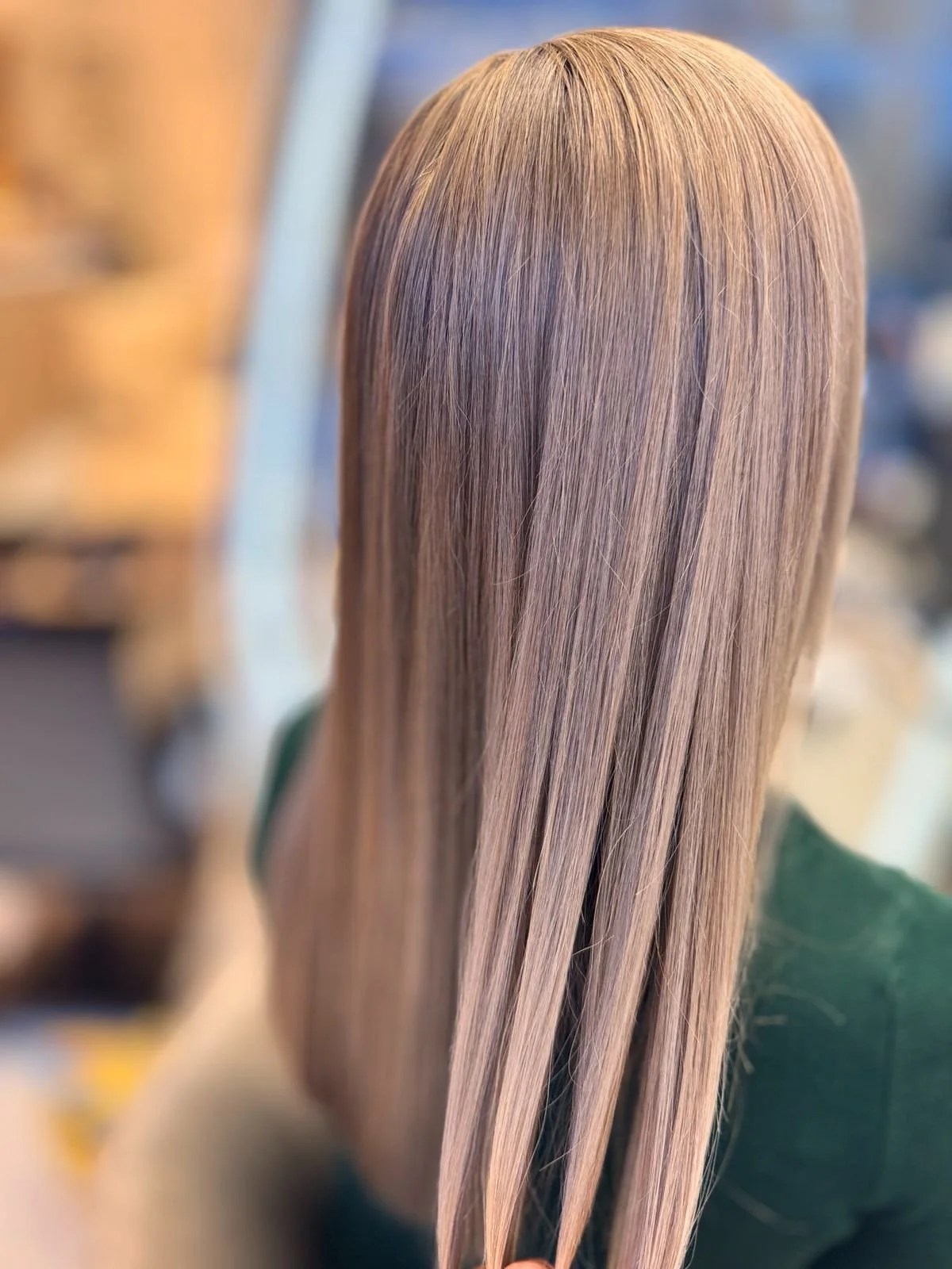 Back view of a person with long, straight, shiny blonde hair.