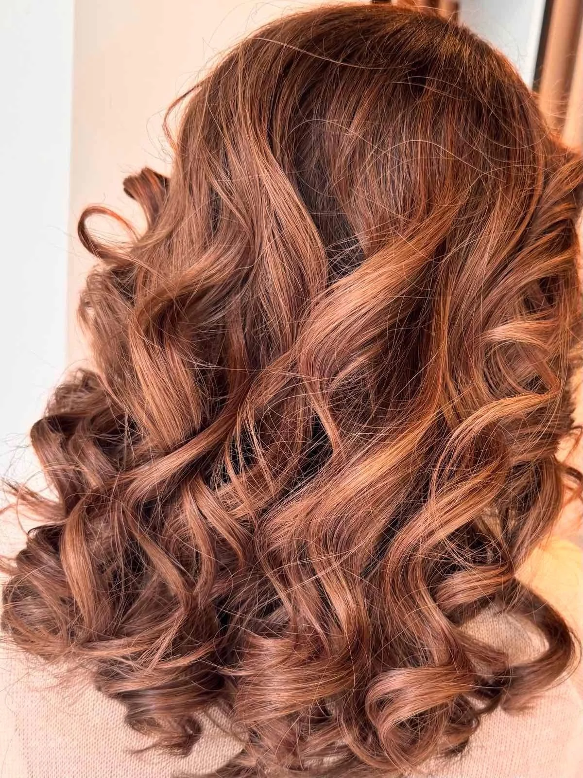 Close-up of a person's wavy, light brown hair with highlights.