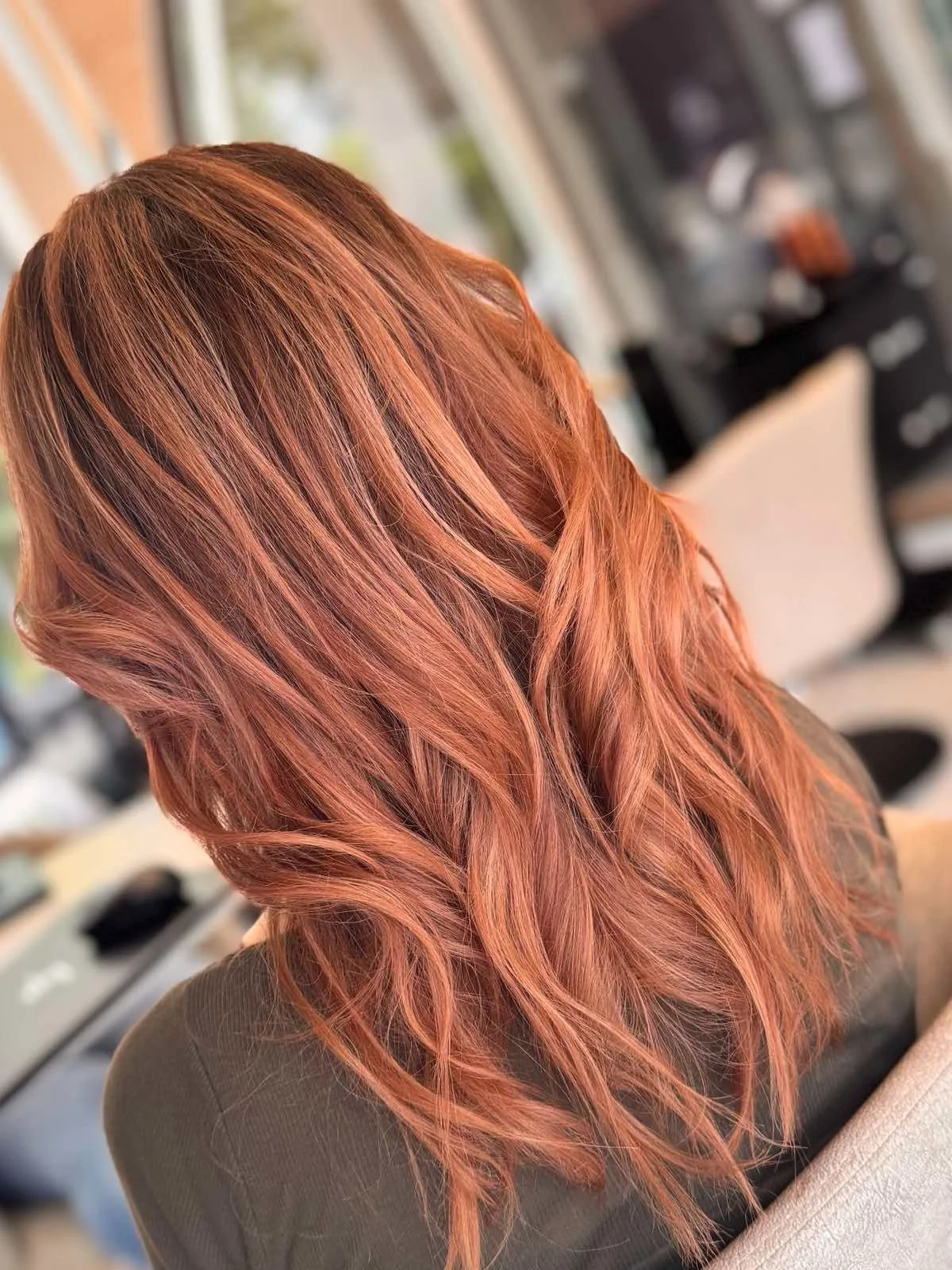 Woman with wavy, reddish hair in a salon setting.