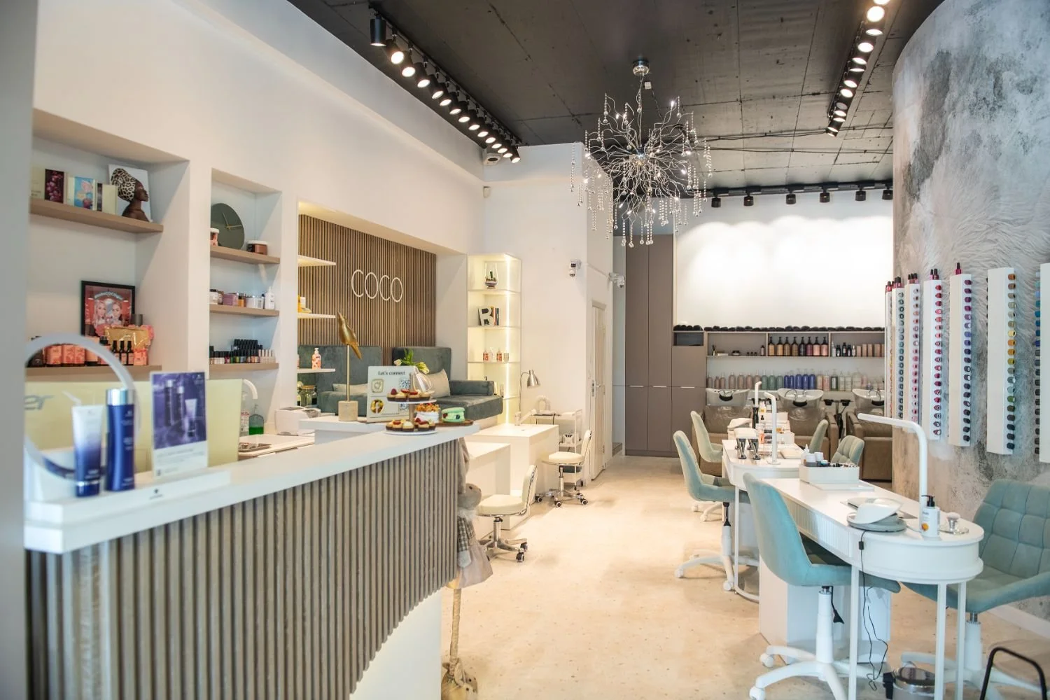 Interior of a beauty salon or nail spa with treatment stations, shelves with nail polish, and modern decor.