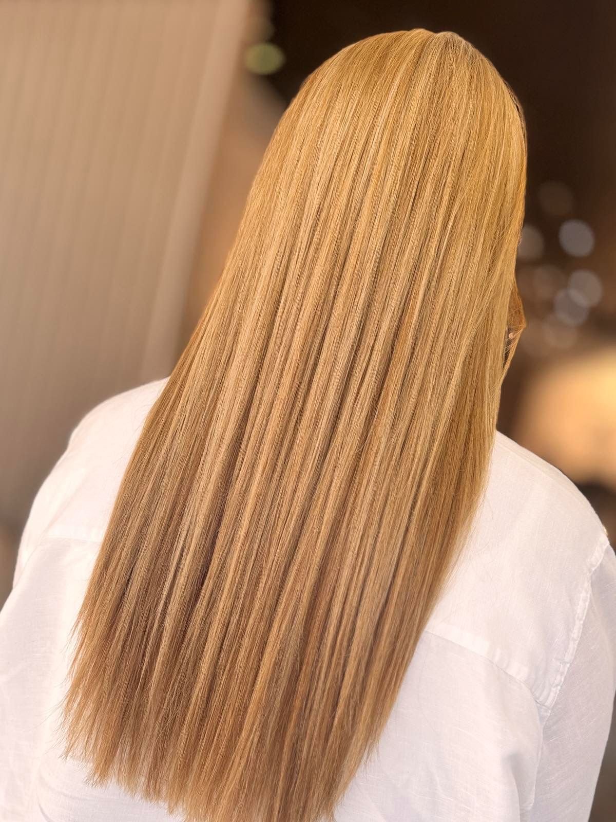 Back of a person's head with long, straight, blonde hair.