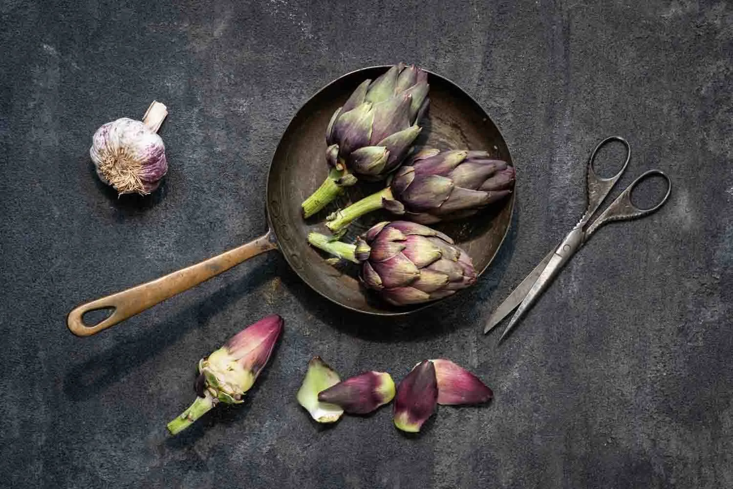 Still life of artichokes, garlic, frying pan and scissors, by Wendy Akers