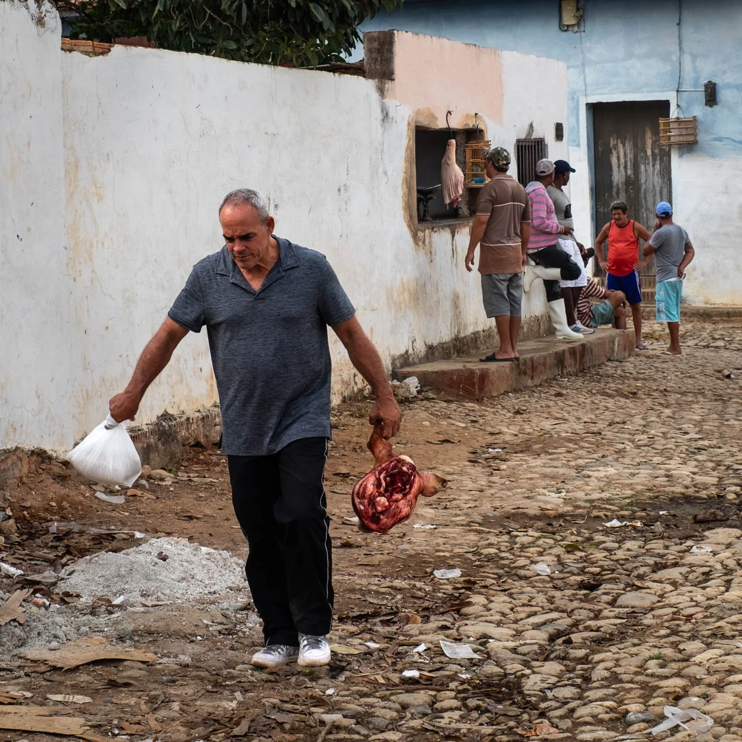 Man leaving Cuban butcher's shop with pig's head