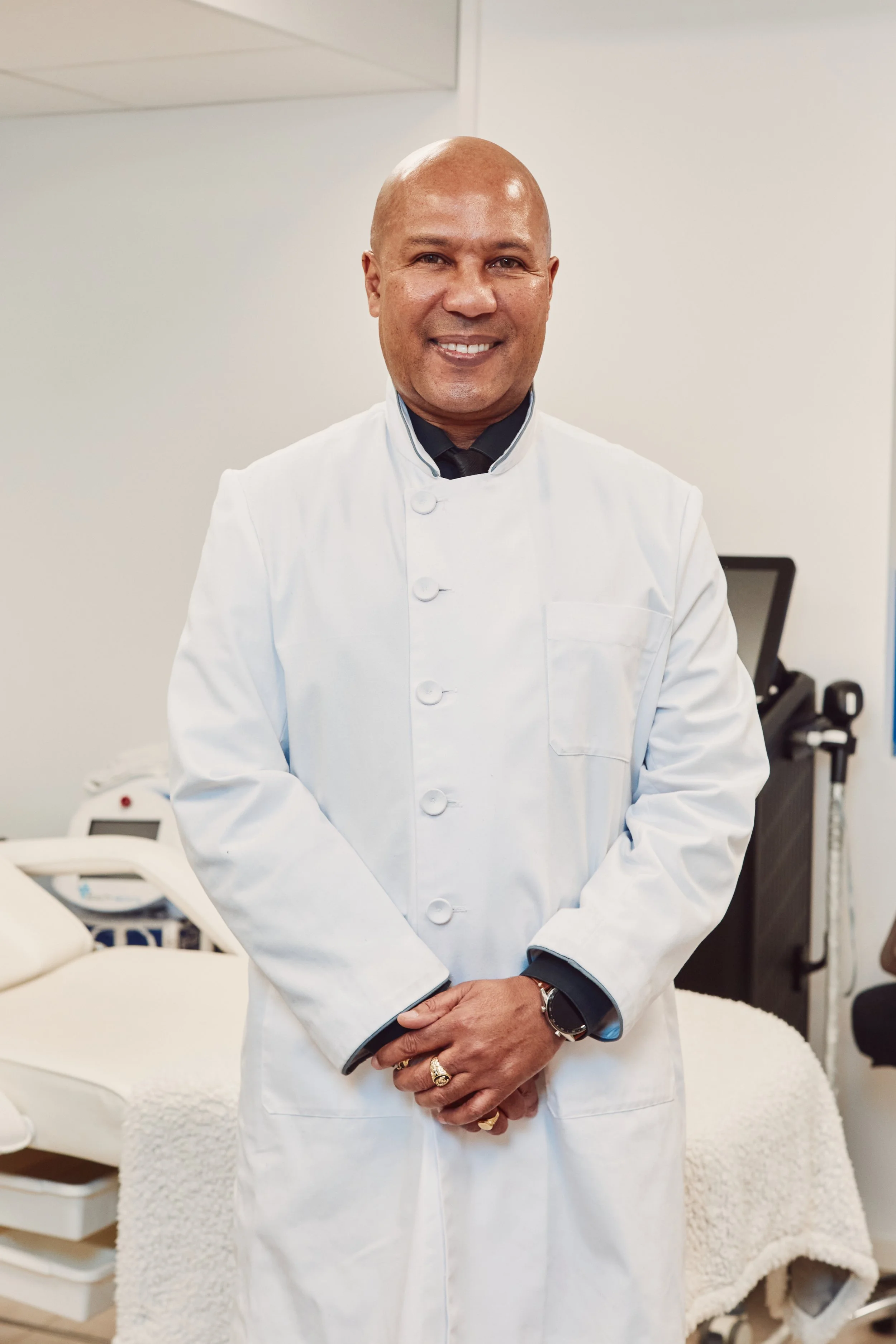 A man in a white medical coat standing in a medical office.