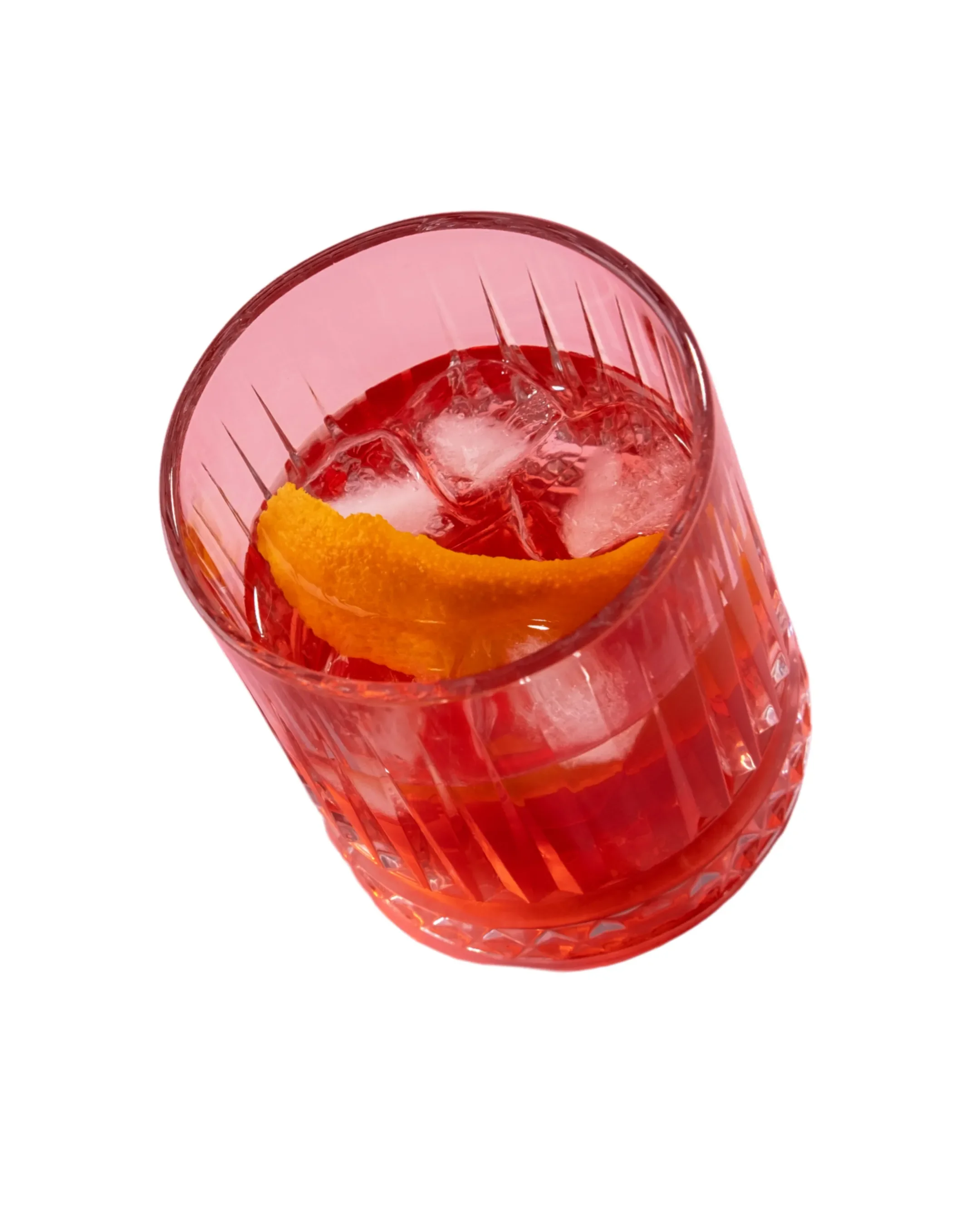 A tall glass with a textured design contains a red beverage with ice cubes and an orange slice garnish.