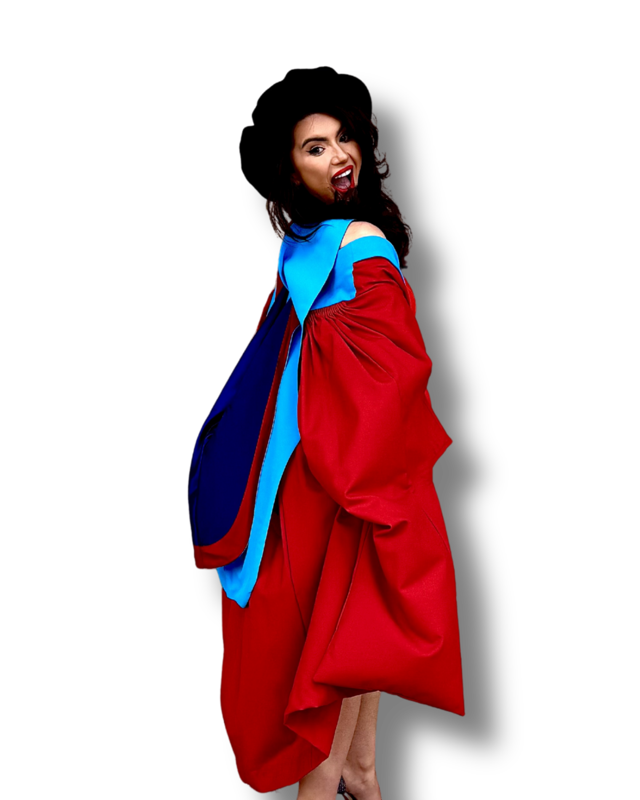 A woman with long dark hair wearing a large black hat and colorful clothing, posing with a playful expression against a black background.