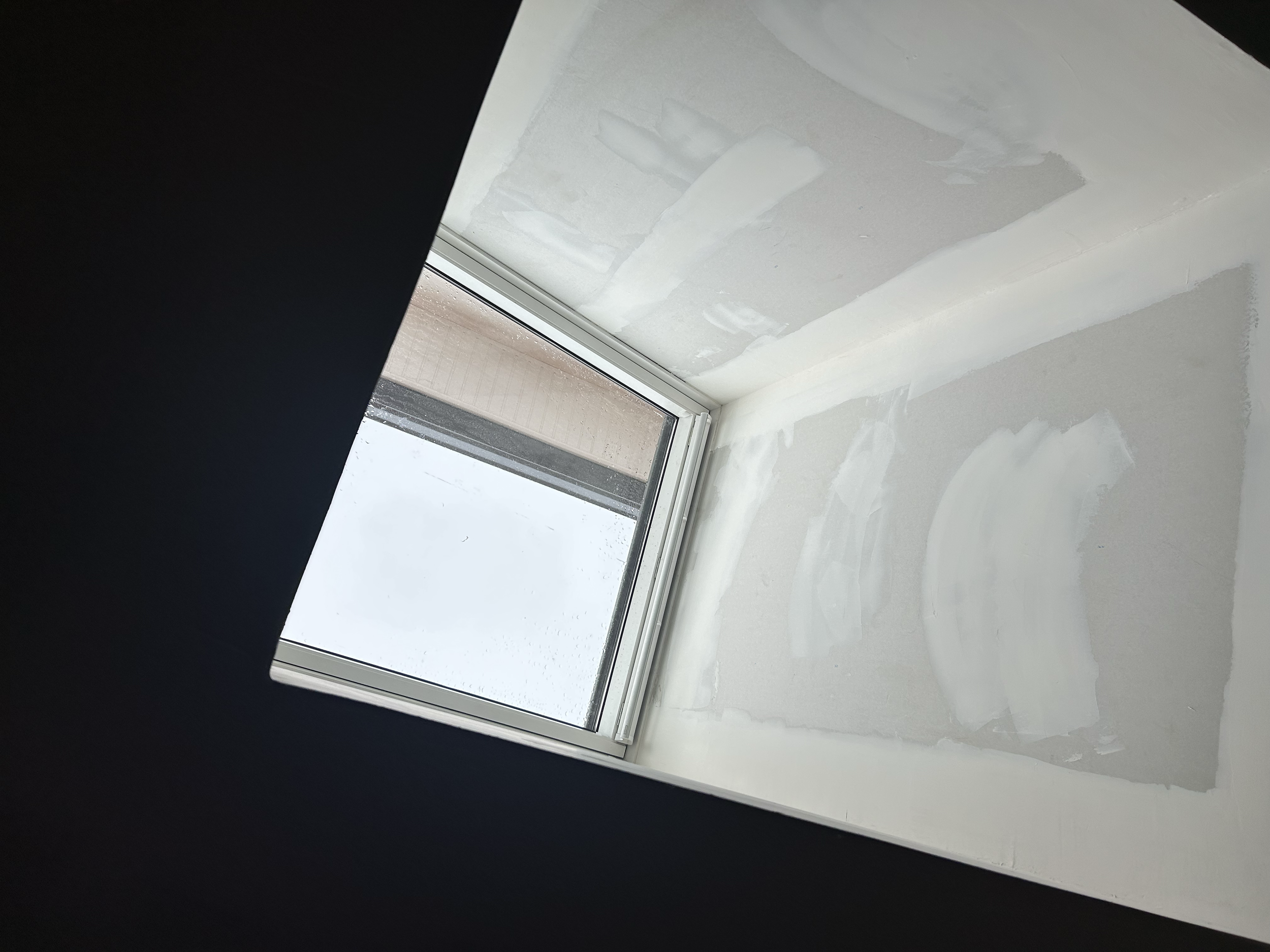 Fenêtre de toit dans une pièce en cours de rénovation avec des murs en cours de peinture.