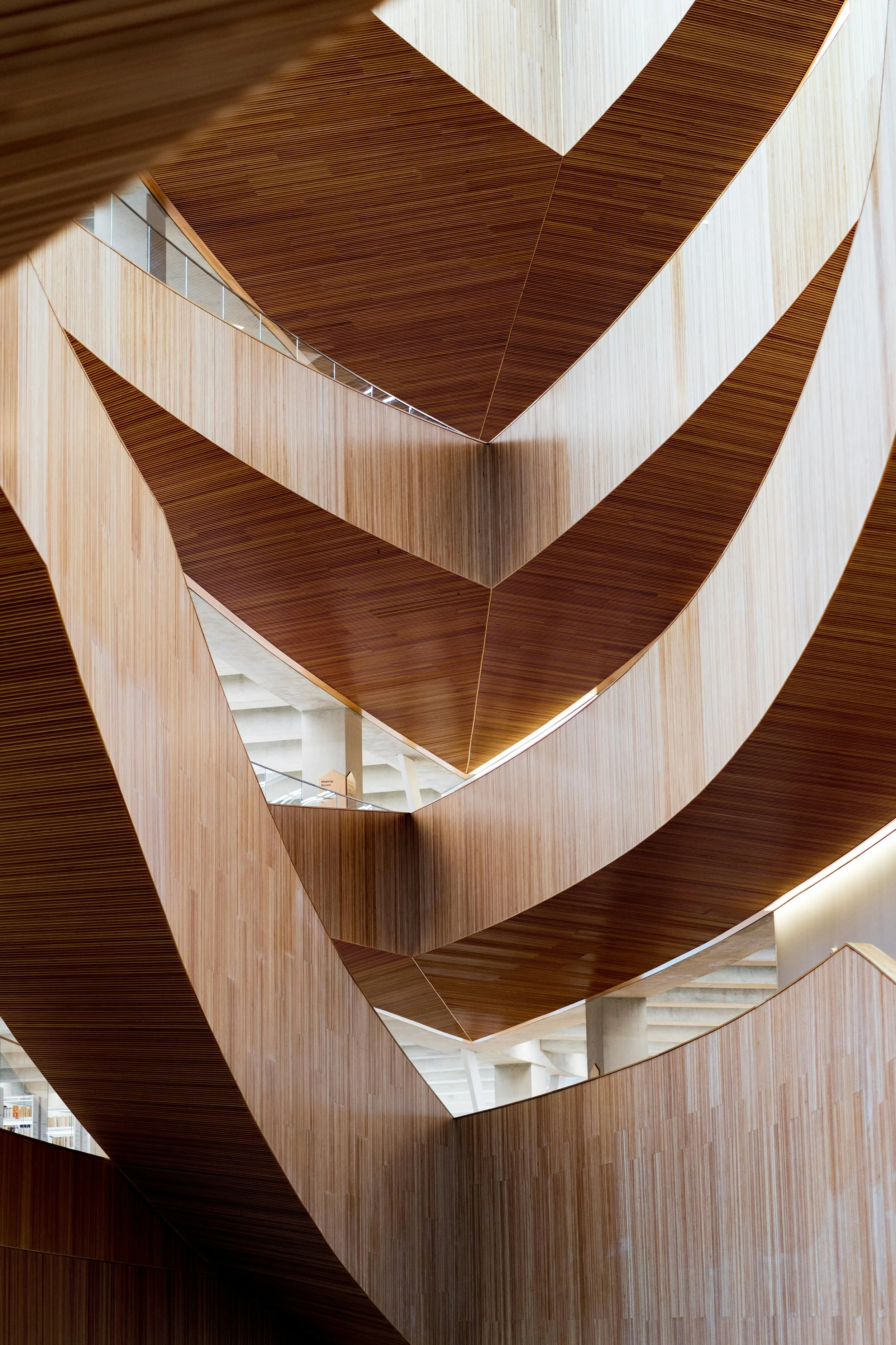 Interior view of a modern building with curved wooden staircases and walkways.
