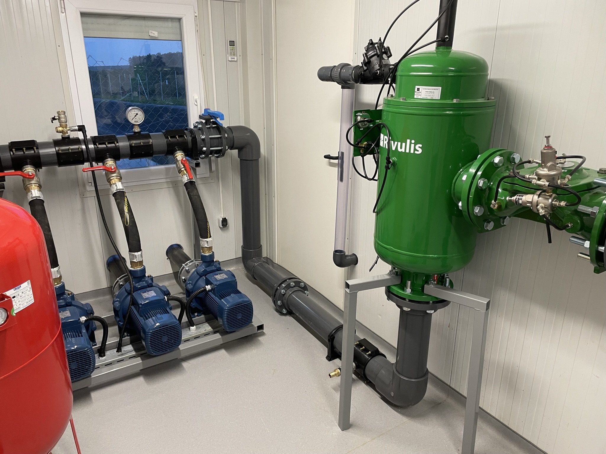 Mechanical room with pipes, pumps, and a green filtration system labeled "Vulis".